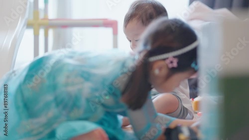 Candid of playful asian children relaxed playing indoors at nursery school. Child Day Care Concept. Active happy kids, brother and sister spending time together on educational toys and snack.