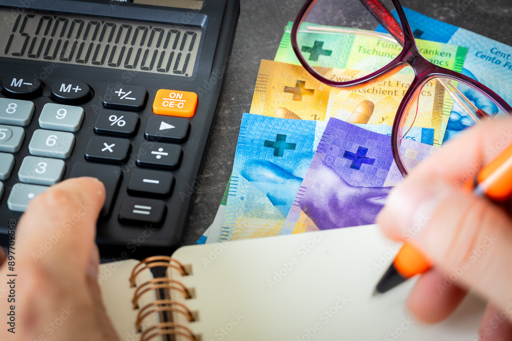 Swiss francs, financial analysis, company accounting, tax calculation, financial business concept. Switzerland money together with a calculator, hand writing down the results in a notebook