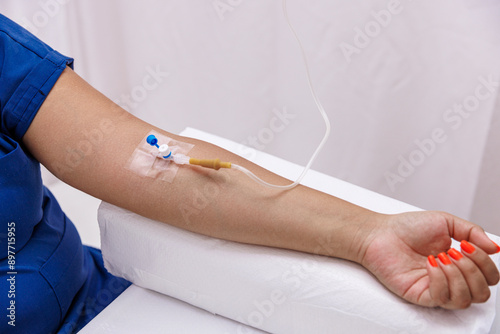 Arm of The patient while receiving an intravenous saline drip to recover from suffering from the illness in the hospital. Medicine, health and people concept. photo