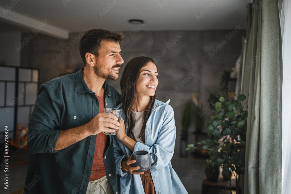 Portrait of couple stand with coffee and water, watch intro the window Portrait of couple stand with coffee and water, watch intro the window