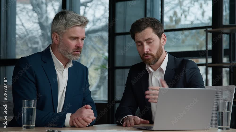 Caucasian men businessmen partners client consultant talking at business meeting in office viewing online project on laptop discussing deal profitable contract shaking hands handshaking cooperation