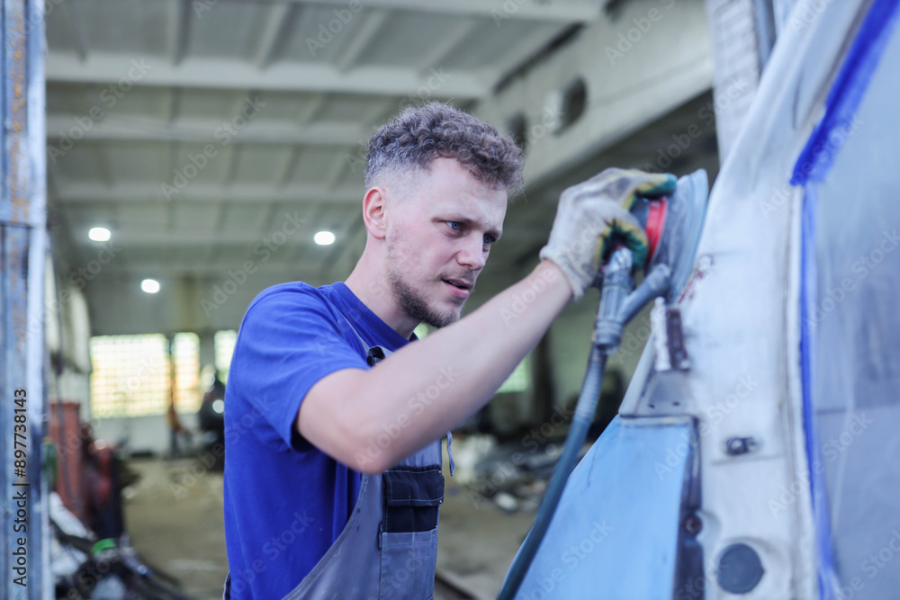 young male master repairs the body of a car van, auto body repair.