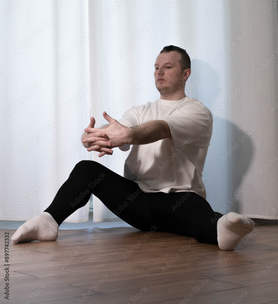 Home yoga pose workouts. A man performs sports exercises with his legs and arms. Male athlete stretches. Home yoga pose workouts. A man performs sports exercises with his legs and arms. Male athlete stretches.
