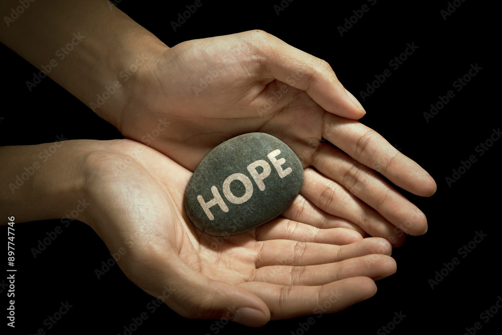 Hand holding hope word on stone with black background Hand holding hope word on stone with black background