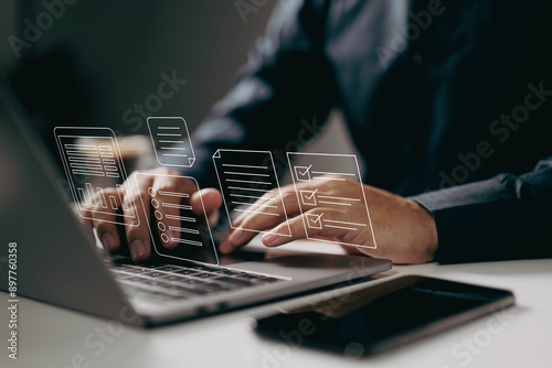 Typing on a laptop with digital documents and checklists floating above. It symbolizes the use of digital tools for task management, organization, and efficient workflow in a modern work environment. photo