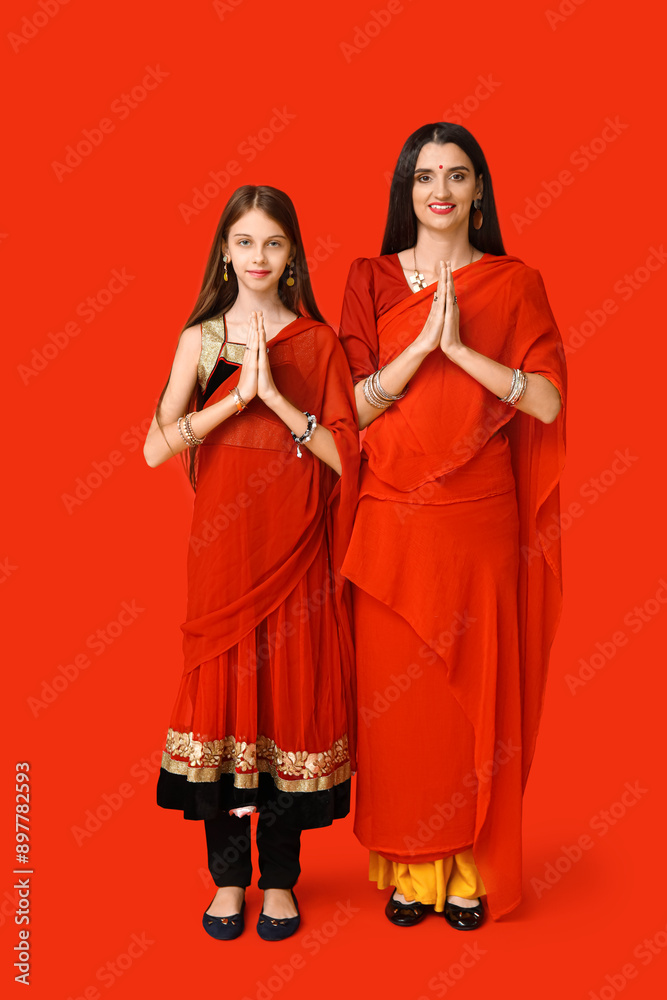 Beautiful mother with her daughter in sari on red background. Divaly celebration Beautiful mother with her daughter in sari on red background. Divaly celebration
