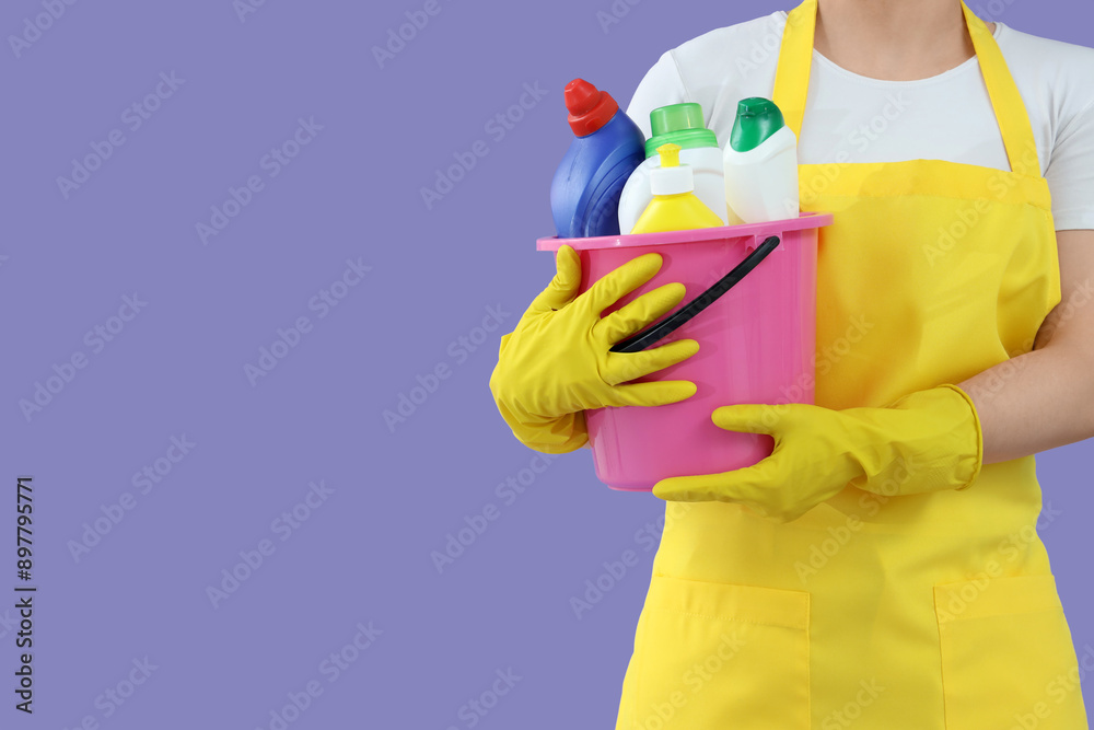 Female janitor with bucket of cleaning supplies on lilac background, closeup Female janitor with bucket of cleaning supplies on lilac background, closeup