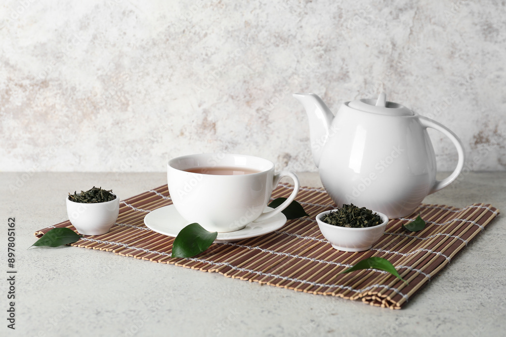 Cup and teapot of hot tea with dried leaves on white background Cup and teapot of hot tea with dried leaves on white background
