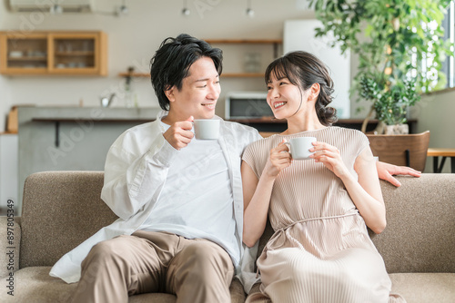 家のリビング・ソファでくつろぐ仲良しの若い日本人夫婦
 photo