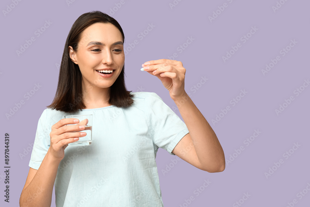 Pretty young woman with glass of water and pill on lilac background Pretty young woman with glass of water and pill on lilac background