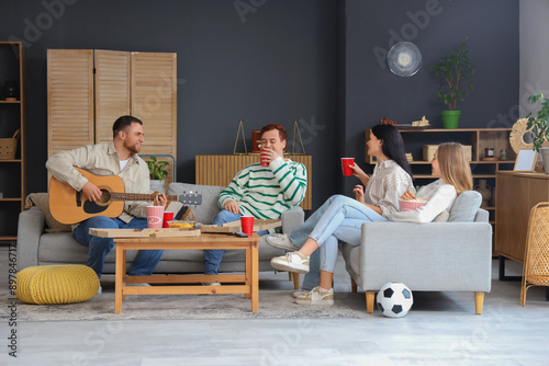 Photography Young man with his friends playing guitar at home party