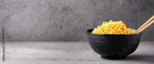 Overhead view of instant noodles with chopsticks laid across, plain white background, copy space, natural lighting photo