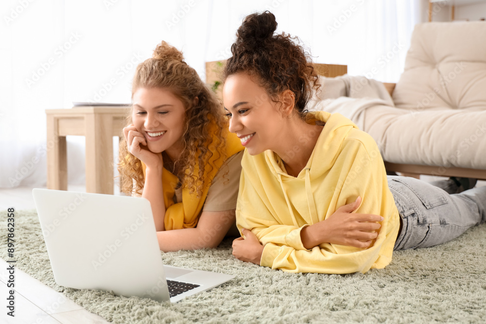 Young women using laptop on floor in living room
