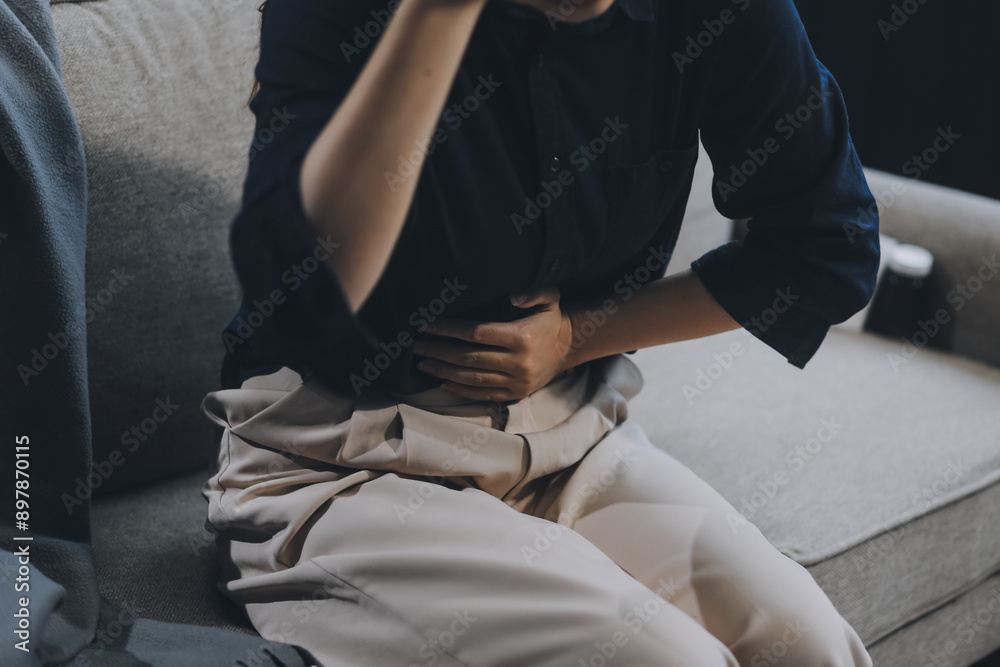 Fototapeta premium A woman with a cold with pills is treated at home chooses which drugs to take and self-medicates, checks the expiration date while sitting on the couch at home