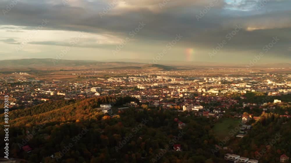 Sunset aerial view of a city surrounded by green hills and vast landscape Sunset aerial view of a city surrounded by green hills and vast landscape