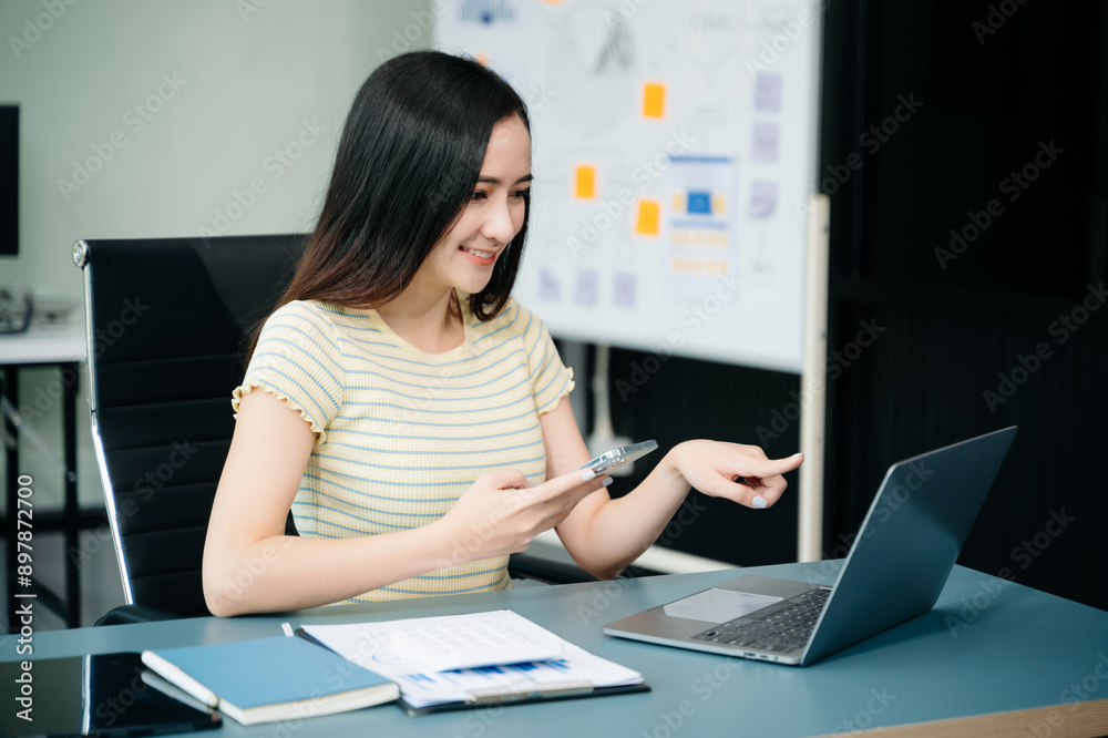 Asian businesswoman working with working notepad, tablet and laptop documents talking on the smartphone, tablet and laptop video call tax