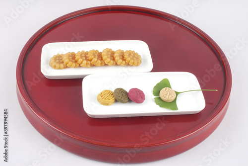 Close-up of Hangwa(Korean traditional sweets and cookies) with ginkgo leaf on white dish and red wood tray, South Korea
 photo