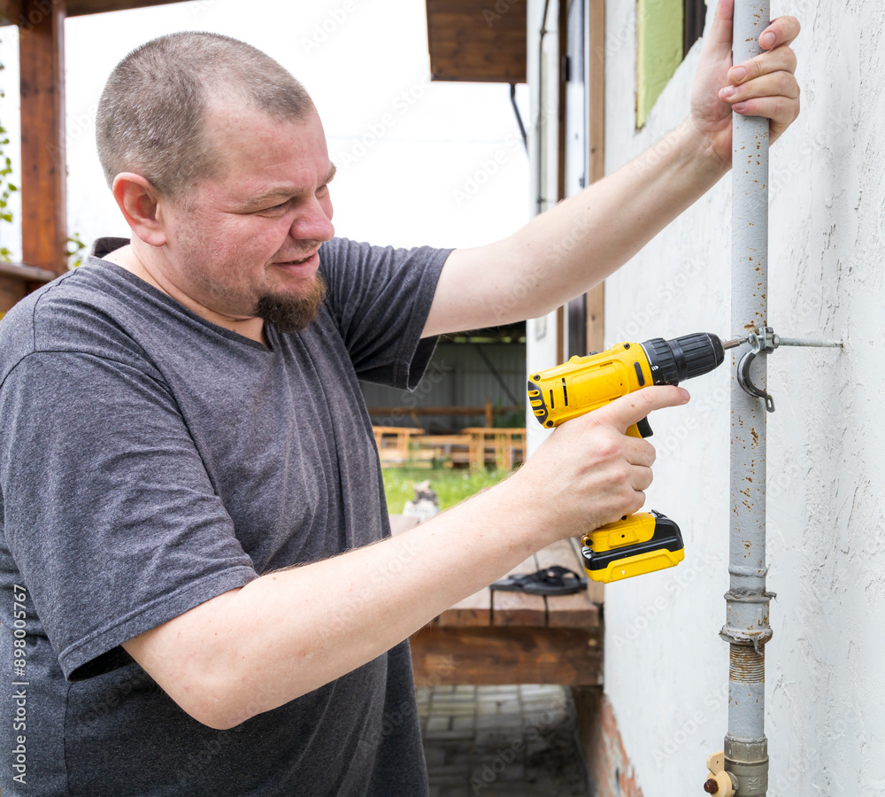 A man is using a drill to fix a pipe A man is using a drill to fix a pipe