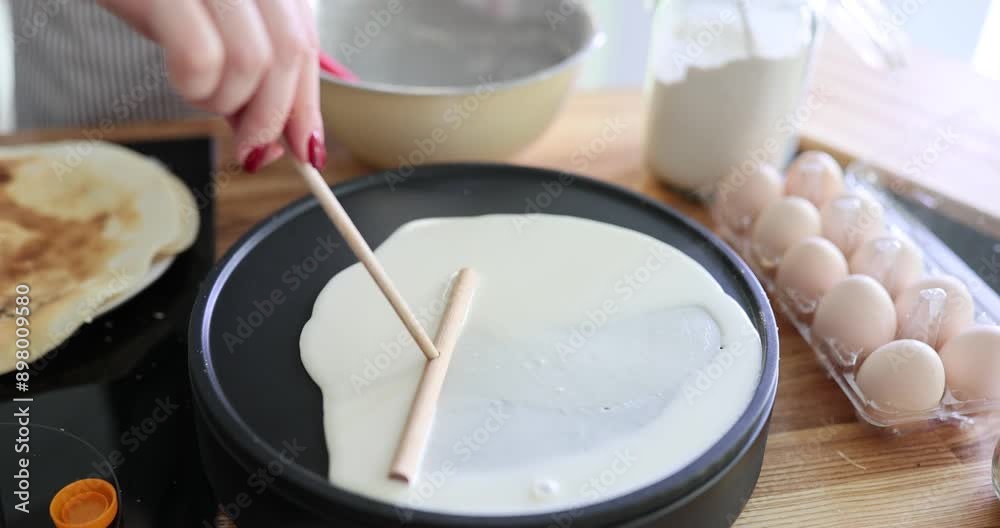 Woman chef spreads pancake batter with spatula in kitchen Woman chef spreads pancake batter with spatula in kitchen