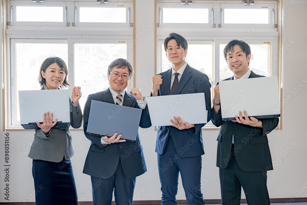 パソコンを持った4人のスーツ男女 パソコンを持った4人のスーツ男女