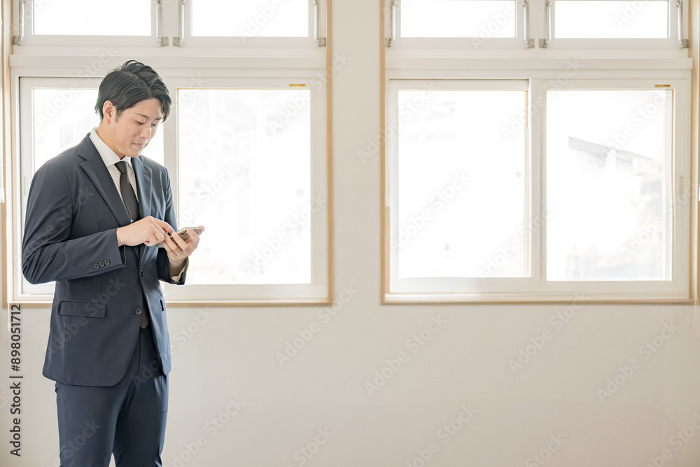 スマホをチェックするスーツの男性 スマホをチェックするスーツの男性