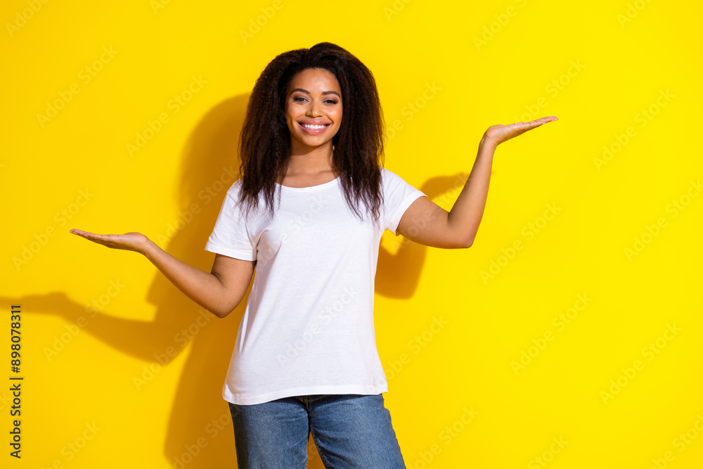 Portrait of nice young woman hold empty space wear t-shirt isolated on yellow color background Portrait of nice young woman hold empty space wear t-shirt isolated on yellow color background