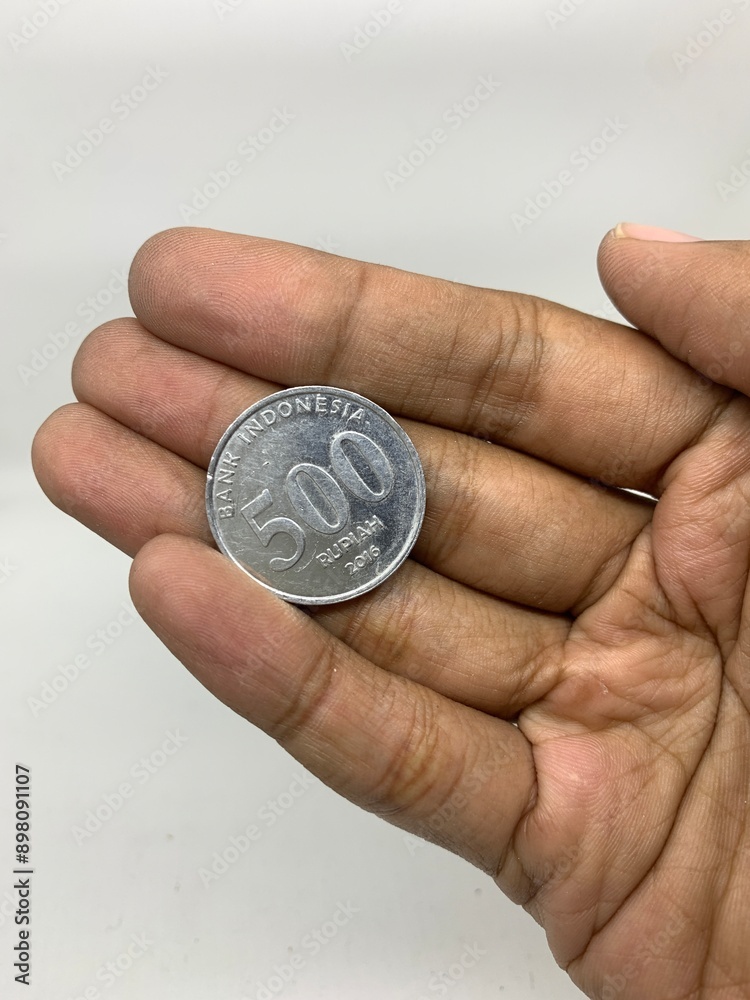 Hand holding one coin in Indonesian rupiah Hand holding one coin in Indonesian rupiah