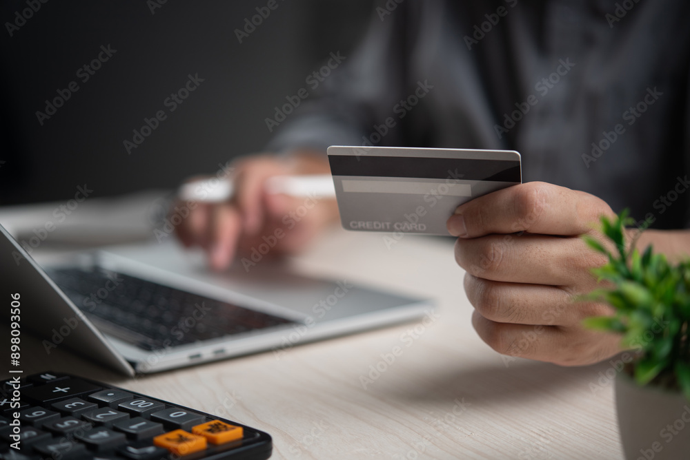 Hand holding a credit card making an online payment using a laptop. E-commerce transaction, digital shopping, secure payment. Modern business and consumer convenience. Hand holding a credit card making an online payment using a laptop. E-commerce transaction, digital shopping, secure payment. Modern business and consumer convenience.