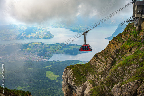 фотографія Cable car approaching Mount Pilatus in Switzerland, with Lake Lucerne visible in the background amidst fog and clouds