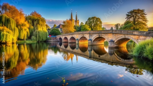 Serene River Avon flows gently beneath historic medieval stone bridge in idyllic Stratford upon Avon scenic morning landscape.