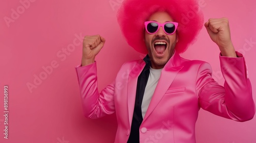 A man in a pink wig and suit is smiling and raising his hands in the air. Concept of joy and celebration