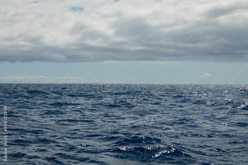 background with blue sea with ripples and waves and blue sky with blanket of clouds background with blue sea with ripples and waves and blue sky with blanket of clouds