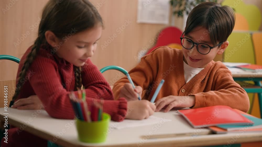 School education studying two funny playing Caucasian little girl daughter child kids children writing in classroom play game drawing fun competition class lesson boy son guy classmates friends write