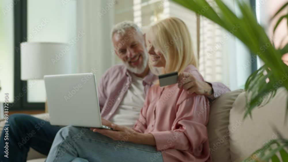 Happy mature smiling senior Caucasian couple elderly family grandparents woman man female male use credit card laptop for payment bill online shopping couch banking e-business remote purchase buy home Happy mature smiling senior Caucasian couple elderly family grandparents woman man female male use credit card laptop for payment bill online shopping couch banking e-business remote purchase buy home
