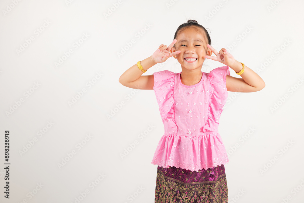 Portrait Thailand kid girl smiling traditional Thai dress costume radiates positivity by forming victory and peace signs, studio shot isolated white background, kindergarten child V sign finger Portrait Thailand kid girl smiling traditional Thai dress costume radiates positivity by forming victory and peace signs, studio shot isolated white background, kindergarten child V sign finger