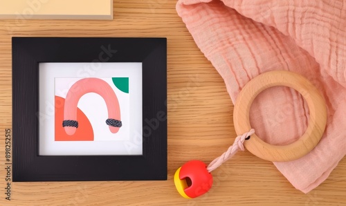 A framed abstract rainbow print with accompanying baby toys and photo