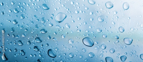 Detailed close up of water droplets on a backdrop of soft blue sky creating an abstract wet texture with bubbles on either smooth plastic or distressed surfaces depicting realistic condensed water dr