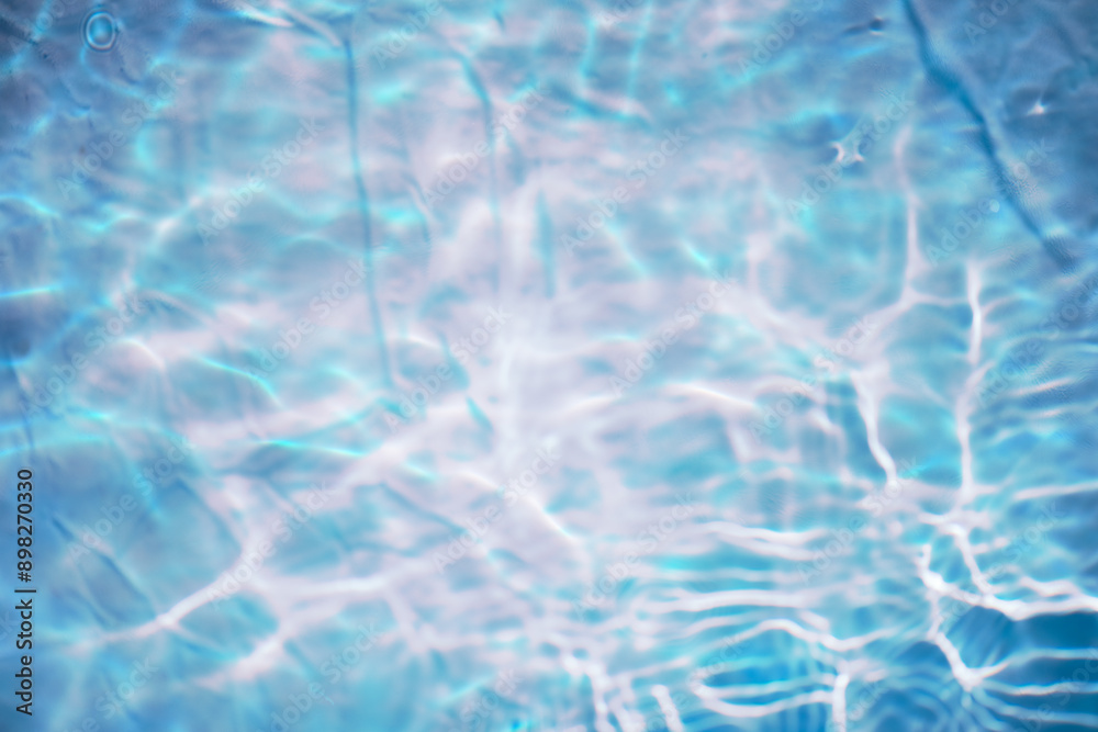 Obraz premium Blue water with ripples on the surface. Defocus blurred transparent blue colored clear calm water surface texture with splashes and bubbles. Water waves with shining pattern texture background.