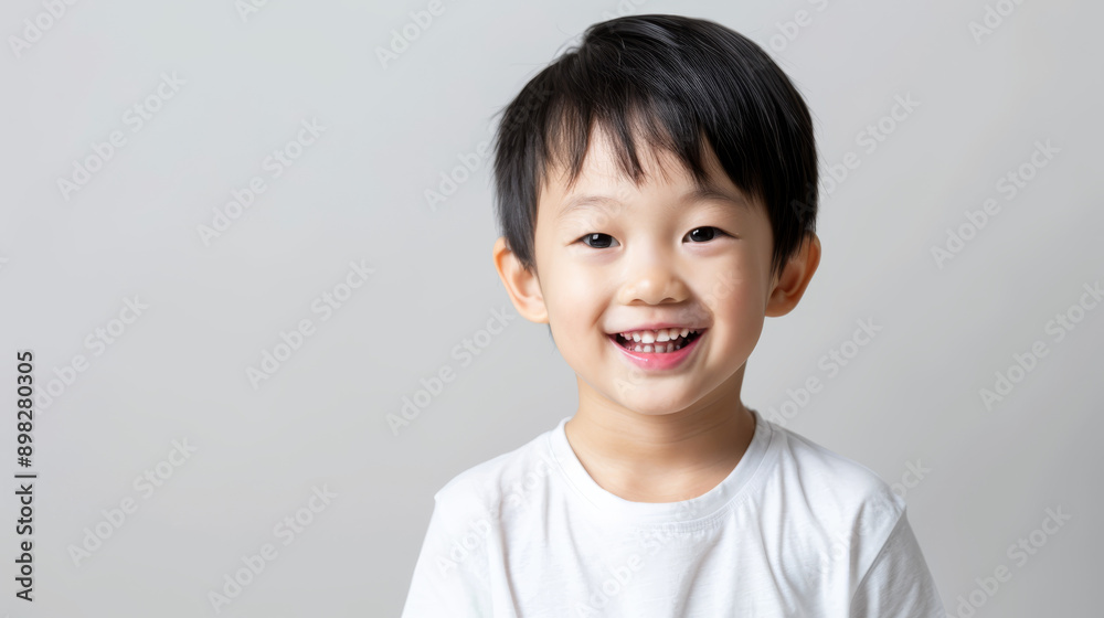 A cheerful child with a bright smile and sparkling eyes, radiating joy and innocence against a simple light grey background. A cheerful child with a bright smile and sparkling eyes, radiating joy and innocence against a simple light grey background.