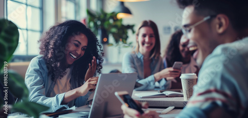 A group of young professionals in an office setting were gathered around one person who was presenting on their tablet to another individual sitting down and smiling at them