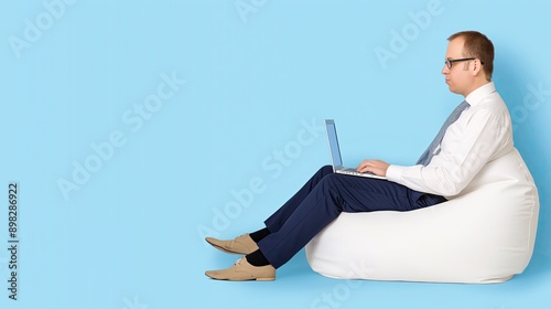 A Businessman Is Hard at Work on His Laptop While Sitting Comfortably in a Beanbag Chair