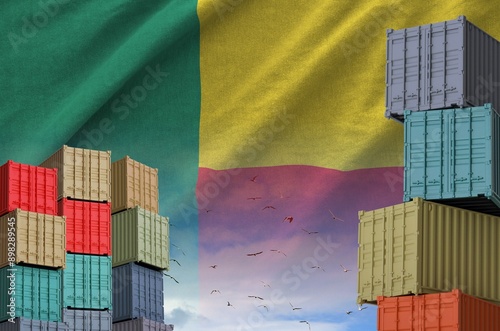 Benin flag and big stack of shipping cargo containers in docks with sky background close up photo