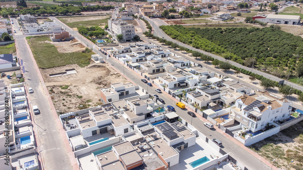 Drone shot of urbanization in Daya Nueva, Spain, showcasing modern residential houses, roads, and surrounding greenery.
Drone shot of urbanization in Daya Nueva, Spain, showcasing modern residential houses, roads, and surrounding greenery.