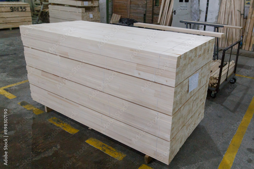 Wooden boards after processing are stacked in large piles in the warehouse of a woodworking plant Wooden boards after processing are stacked in large piles in the warehouse of a woodworking plant