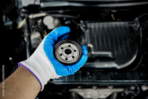 Top view of gloved man's hand holding the oil filter of a car. Close-up of a new oil filter in the hands of a mechanic, changing it in the car for car maintenance.