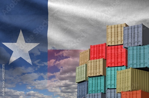 Texas US state flag and big stack of shipping cargo containers in docks with sky background close up photo