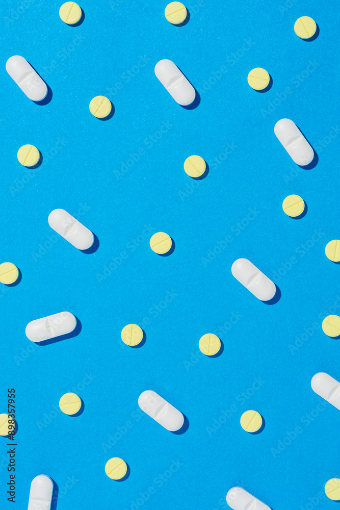 White and yellow tablet pills on blue background. White and yellow tablet pills on blue background.