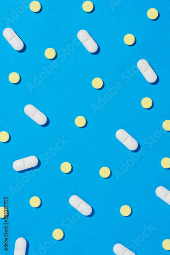 White and yellow tablet pills on blue background.