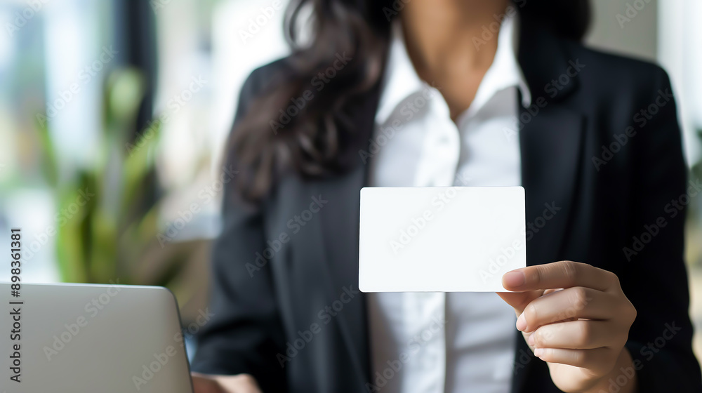 Businesswoman holding and showing a blank business cards while working in office