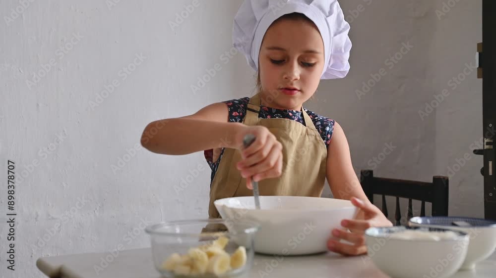 Young girl wearing chef hat and apron preparing a meal in the kitchen Young girl wearing chef hat and apron preparing a meal in the kitchen